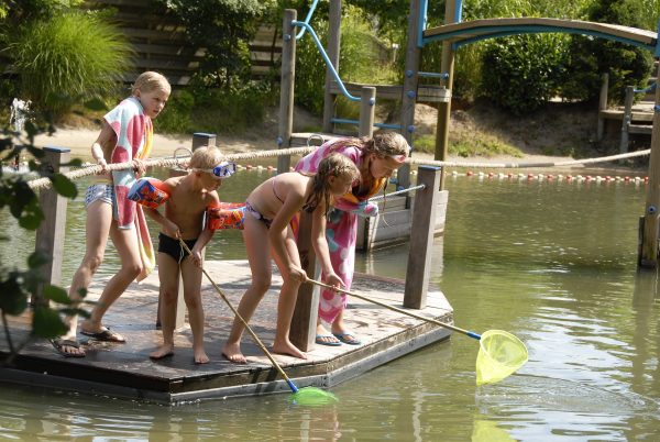 Kinder spielen am Badesee mit einander